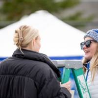 A Career Center student employee interviews and alum on a ladder